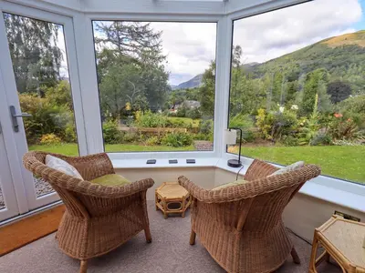 a room with two chairs and a table in front of a window at Sandburne Cottage in Keswick