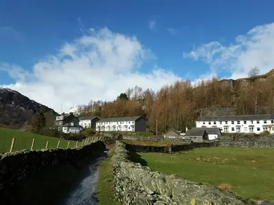 a village with a stone wall and a river at Mellbreak in Chapel Stile