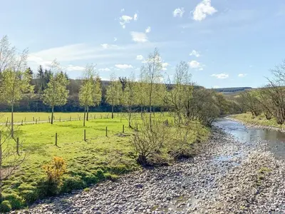a river flows through a grassy field next to a creek at Pinclanty Cottage in Pinmore