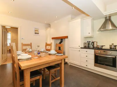a kitchen with a wooden table with chairs and appliances at Holme Rigg in Keswick