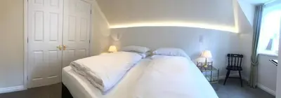 a bedroom with a white bed with two pillows at Manyleith Rig Cottage in Polmood