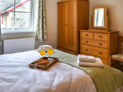 a tray of food and two glasses of orange juice on a bed at The Old Workshop in Keswick