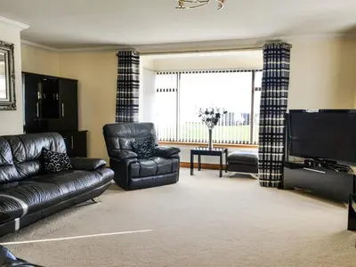 a living room with black leather furniture and a flat screen tv at Ashgrove in Mainsriddle