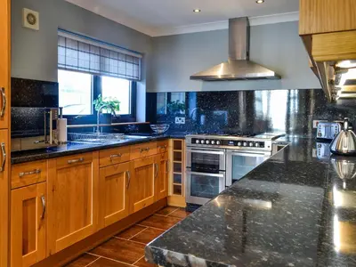a kitchen with wooden cabinets and a counter top at Ashgrove in Mainsriddle