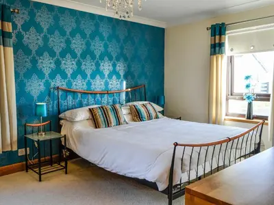 a bedroom with a bed with a blue wall at Ashgrove in Mainsriddle