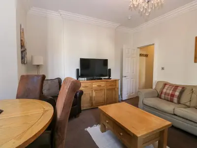 a living room with a tv and a couch and a table at Carlton House Apartment 1 in Keswick