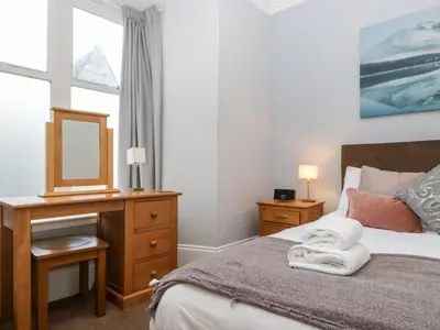 a bedroom with a bed with a dresser and a mirror at Carlton House Apartment 1 in Keswick
