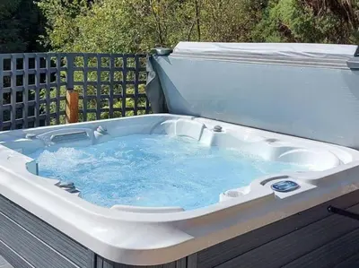a hot tub with blue water in it at Treetops Luxury Log Cabin - Hot tub, BBQ & Sauna in Kippford