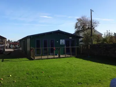 a green building with a fence in a yard at Ryans Retreat, Bowness on Solway perfect for a break when walking Hadrians Wall with a hot tub in Bowness-on-Solway