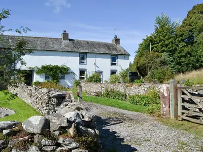 a white house with a stone wall and a fence at The Retreat in Sunderland