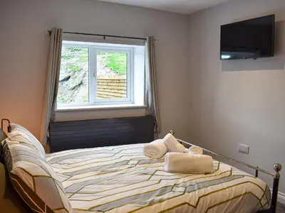 a bedroom with a bed with a window and a television at Ivy House in Dockray