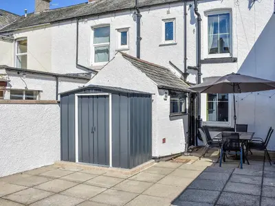 a patio with an umbrella and a table and a building at Long Rose in Keswick