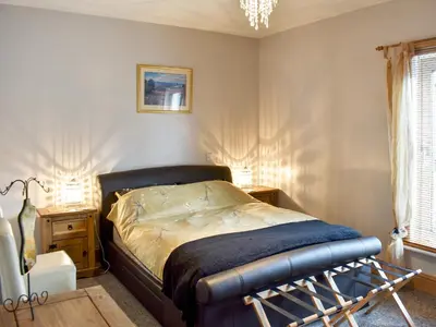 a bedroom with a bed and a table with two lamps at Long Rose in Keswick