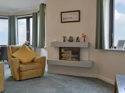 a living room with a fireplace and a chair at Harbour Watch in Maryport