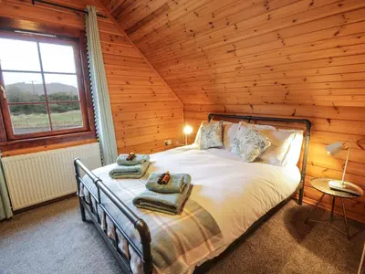 a bedroom with a bed in a log cabin at Moyle Lodge in Dalbeattie