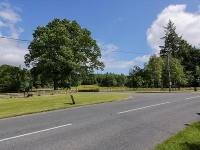 an empty road with a fence and trees at Moyle Lodge in Dalbeattie