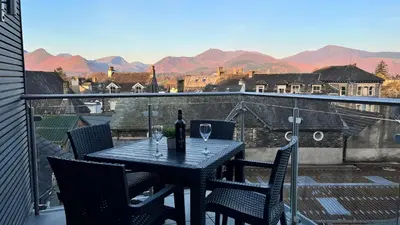 a table with a bottle of wine on a balcony at Ridge View - Amazing Roof Terrace in Keswick