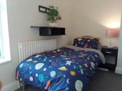 a bedroom with a bed with a blue comforter at Luxury House Near City Center Hospital &Superstore in Carlisle
