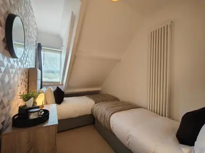 a bedroom with two beds and a mirror at Grove House in Egremont