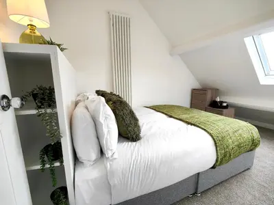 a bedroom with a bed with white sheets and pillows at Grove House in Egremont