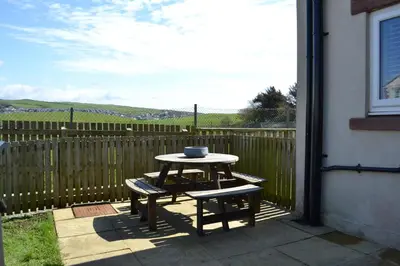 a table and bench on a patio with a fence at Normsy Place Seaside Serenity Breath Taking Views in St Bees