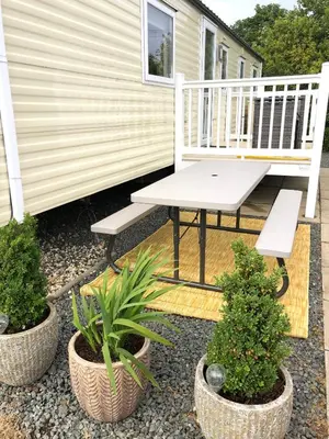 a porch with a bench and two potted plants at Turnberry Holiday Home in Turnberry