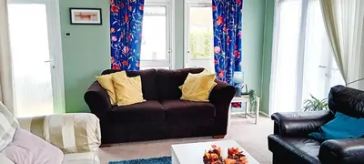 a living room with a brown couch and a window at 24 The Zen Den Cumbria in High Hesket