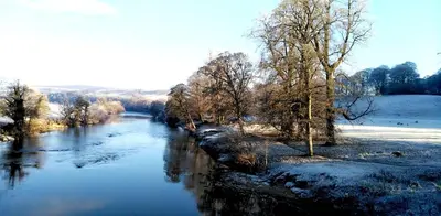 a river with snow and trees on the side of it at 24 The Zen Den Cumbria in High Hesket