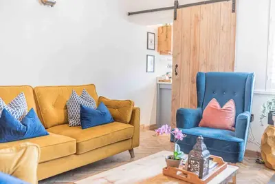 a living room with a couch and two blue chairs at Teapot Cottage in Ennerdale - Hot tub Pizza Oven Log Burner in Cleator