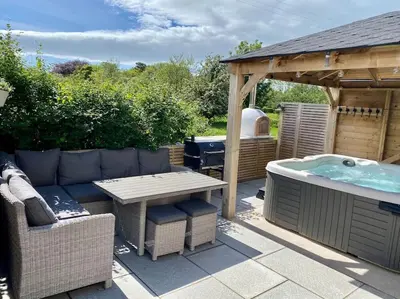 a patio with a jacuzzi tub and a picnic table at Teapot Cottage in Ennerdale - Hot tub Pizza Oven Log Burner in Cleator