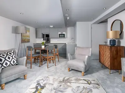 a living room with a table and chairs and a kitchen at Apartment 1 Latrigg in Keswick