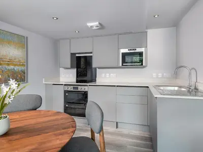 a kitchen with white cabinets and a wooden table at Apartment 1 Latrigg in Keswick
