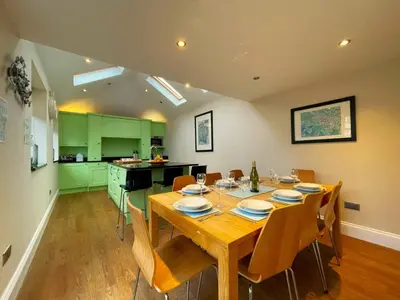 a dining room with a wooden table and green cabinets at Wordsworth House HOT TUB HIRE AVAILABLE in Keswick