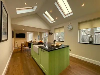 an open kitchen with green cabinets and skylights at Wordsworth House HOT TUB HIRE AVAILABLE in Keswick