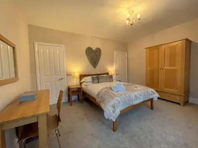 a bedroom with a bed and a table and a desk at Wordsworth House HOT TUB HIRE AVAILABLE in Keswick