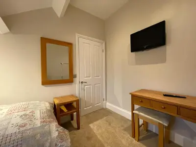 a bedroom with a bed and a dresser and a television at Wordsworth House HOT TUB HIRE AVAILABLE in Keswick