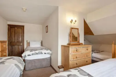 a bedroom with two beds and a mirror and a dresser at The Mountain Cottages - Sawyers in Coniston