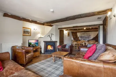 a living room with leather furniture and a fireplace at The Mountain Cottages - Sawyers in Coniston