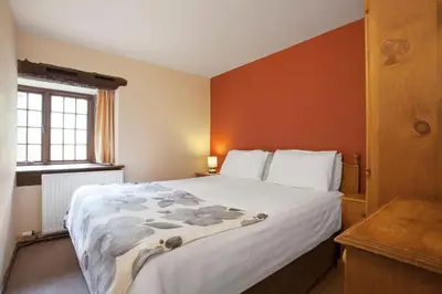a bedroom with a large bed with orange walls at The Mountain Cottages - Millrace in Coniston