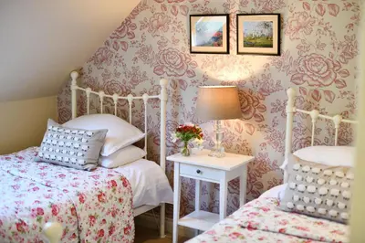 a bedroom with two beds and a table with a lamp at Stables Cottage in Stranraer