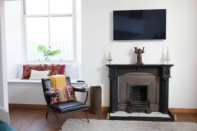 a living room with a black fireplace and a chair at Creathie Cathcart - Georgian Luxury at the beach in Ayr