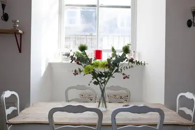 a dining room table with chairs and a vase of flowers at Creathie Cathcart - Georgian Luxury at the beach in Ayr