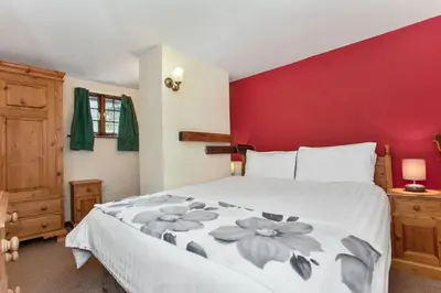 a bedroom with a large bed with a red wall at The Mountain Cottages - Pelton Wheel in Coniston