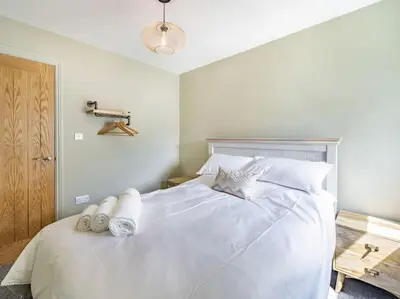 a bedroom with a large white bed with white pillows at Northdene - 5 star Lake District Cottage in Cockermouth