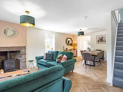 a living room with a green couch and a fireplace at Northdene - 5 star Lake District Cottage in Cockermouth