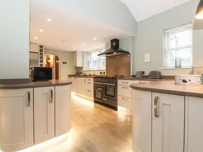 a large kitchen with white cabinets and wooden floors at Blencathra in Keswick
