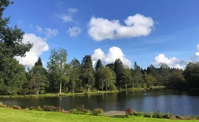 a large lake in a park with trees and clouds at 4 Bed House - Sleeps 9 - HotTub - Parking in Beattock