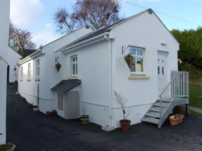 a white house with a staircase next to it at Pinfold Holiday Cottage in Laxey