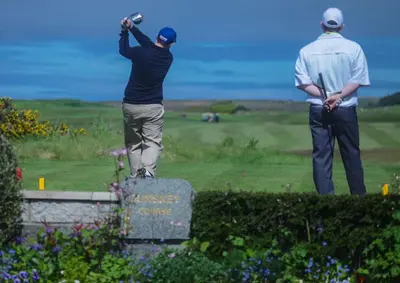 two men standing on top of a sign with a golfer at Cedar Lodge in Portpatrick