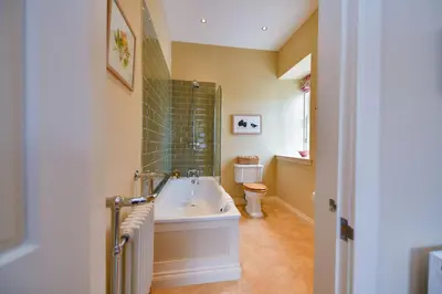 a bathroom with a bath tub and a toilet at Garden Cottage in Stranraer